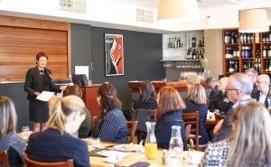 A woman is giving a presentation to a group of people in a restaurant.