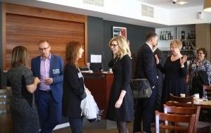 A group of people are standing in a room talking to each other.