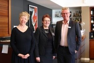 Three people are standing next to each other in a room.