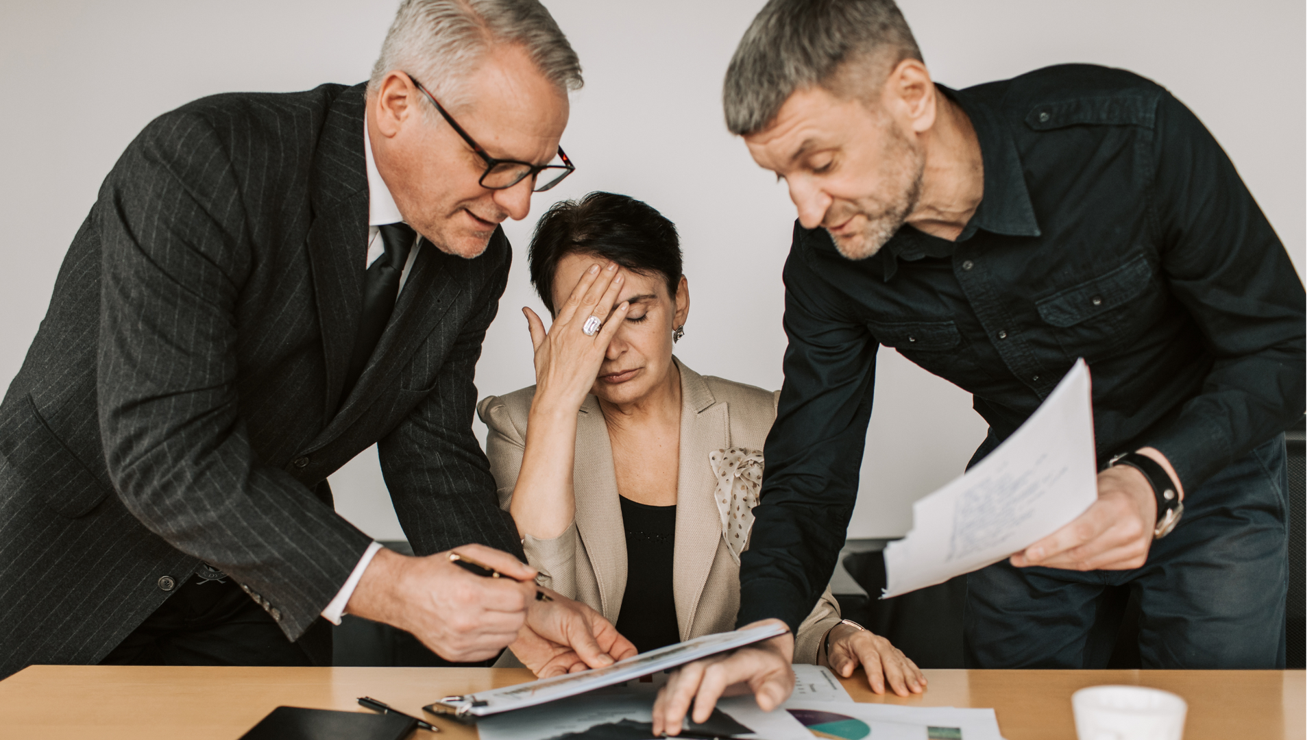 Three men and a woman are sitting at a table looking at papers.