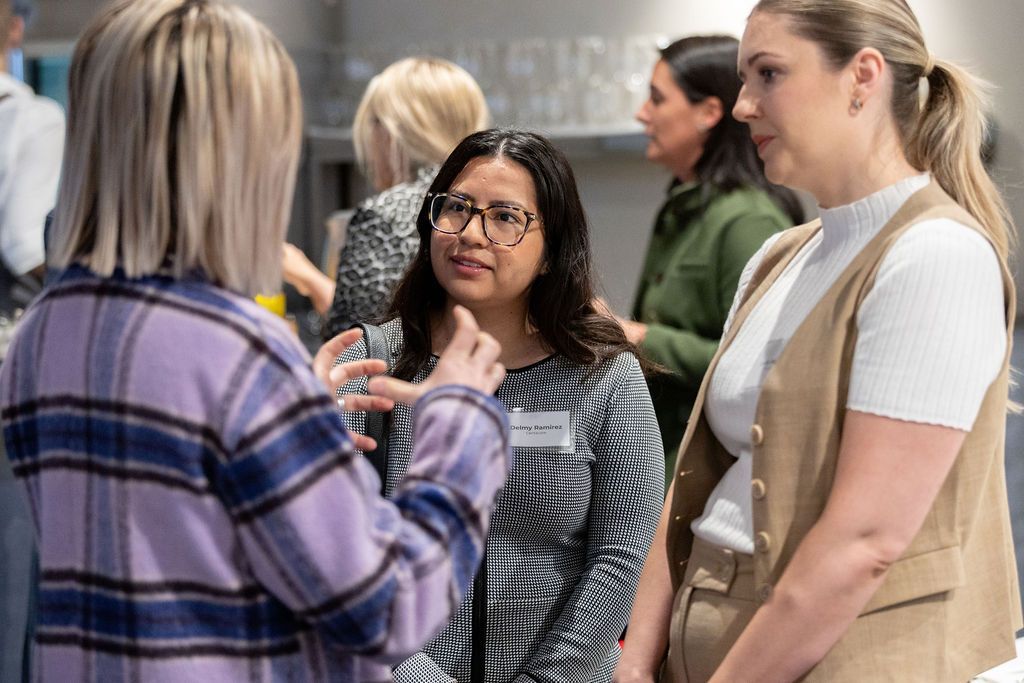A group of women are standing next to each other talking to each other.