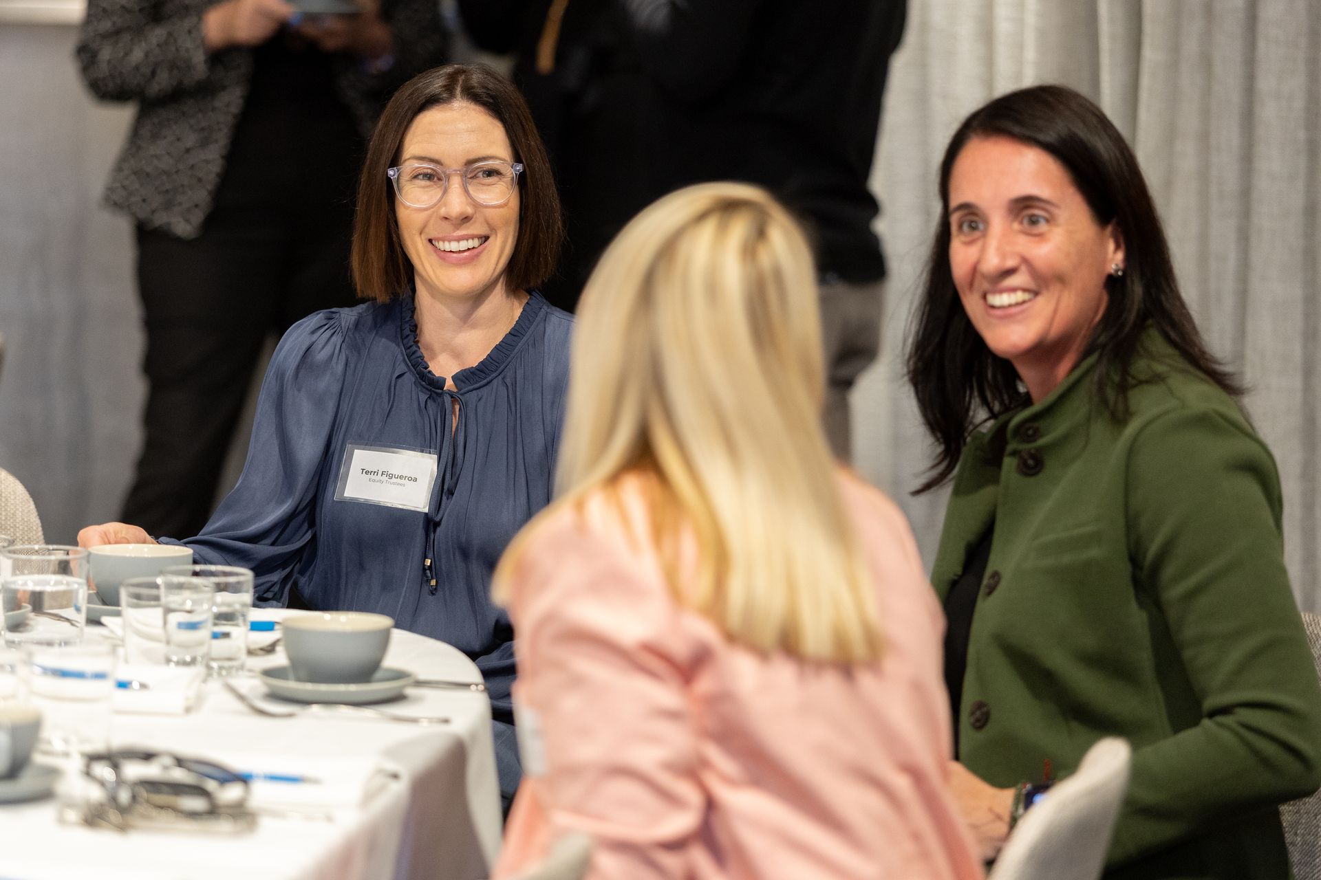 Three women are sitting at a table talking to each other.