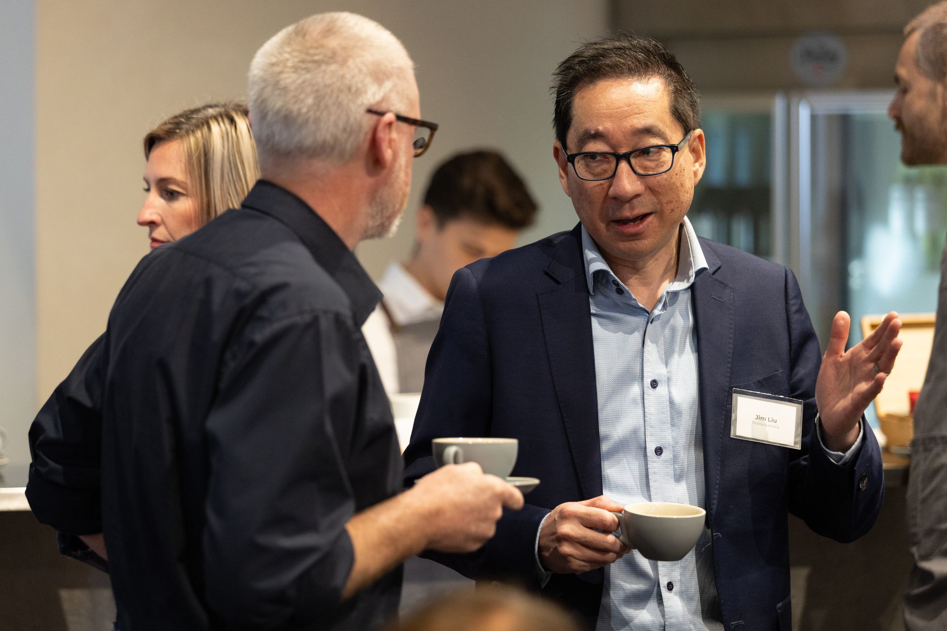 Two men are talking to each other while holding cups of coffee.