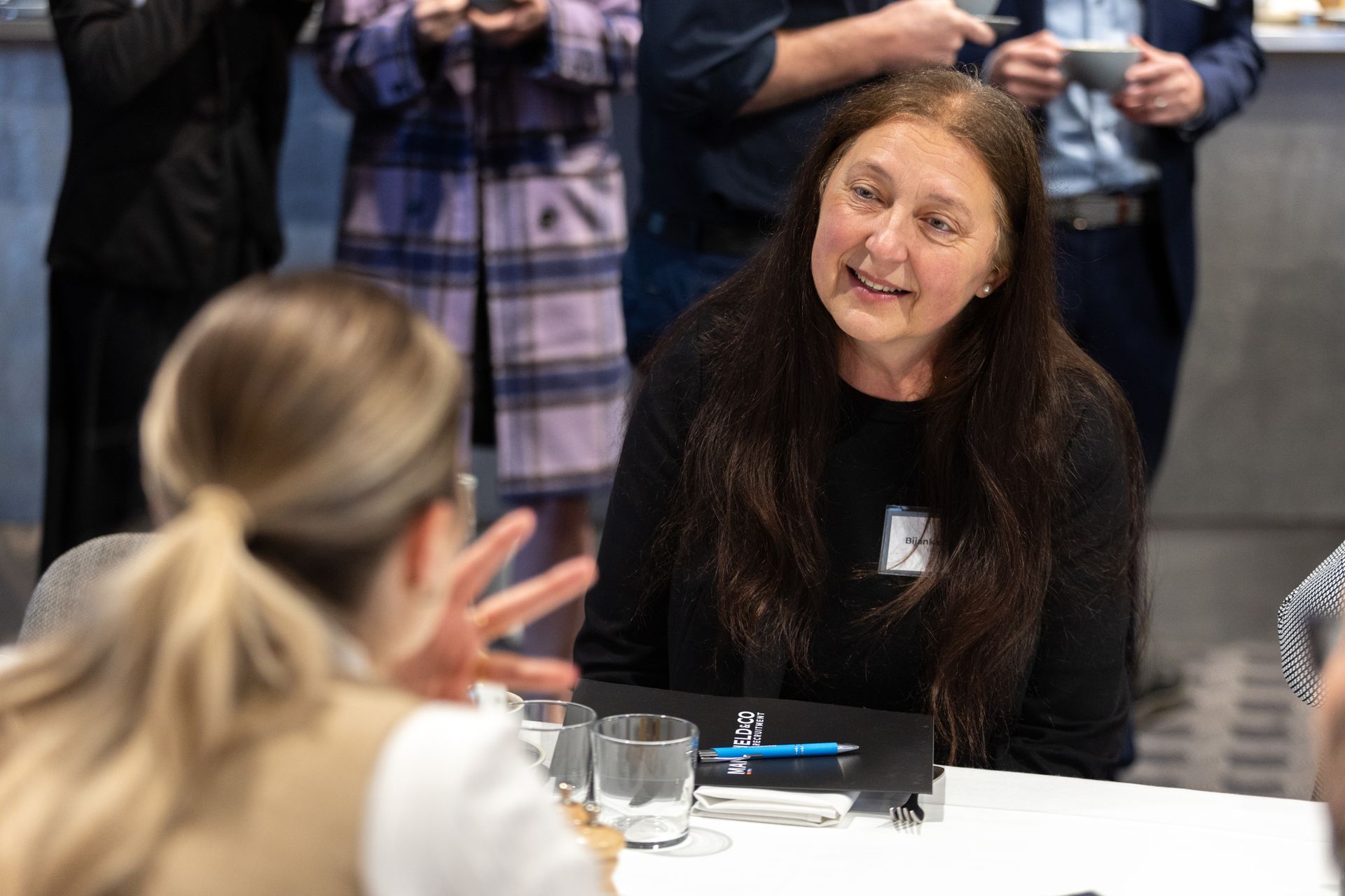 A woman is sitting at a table talking to another woman.
