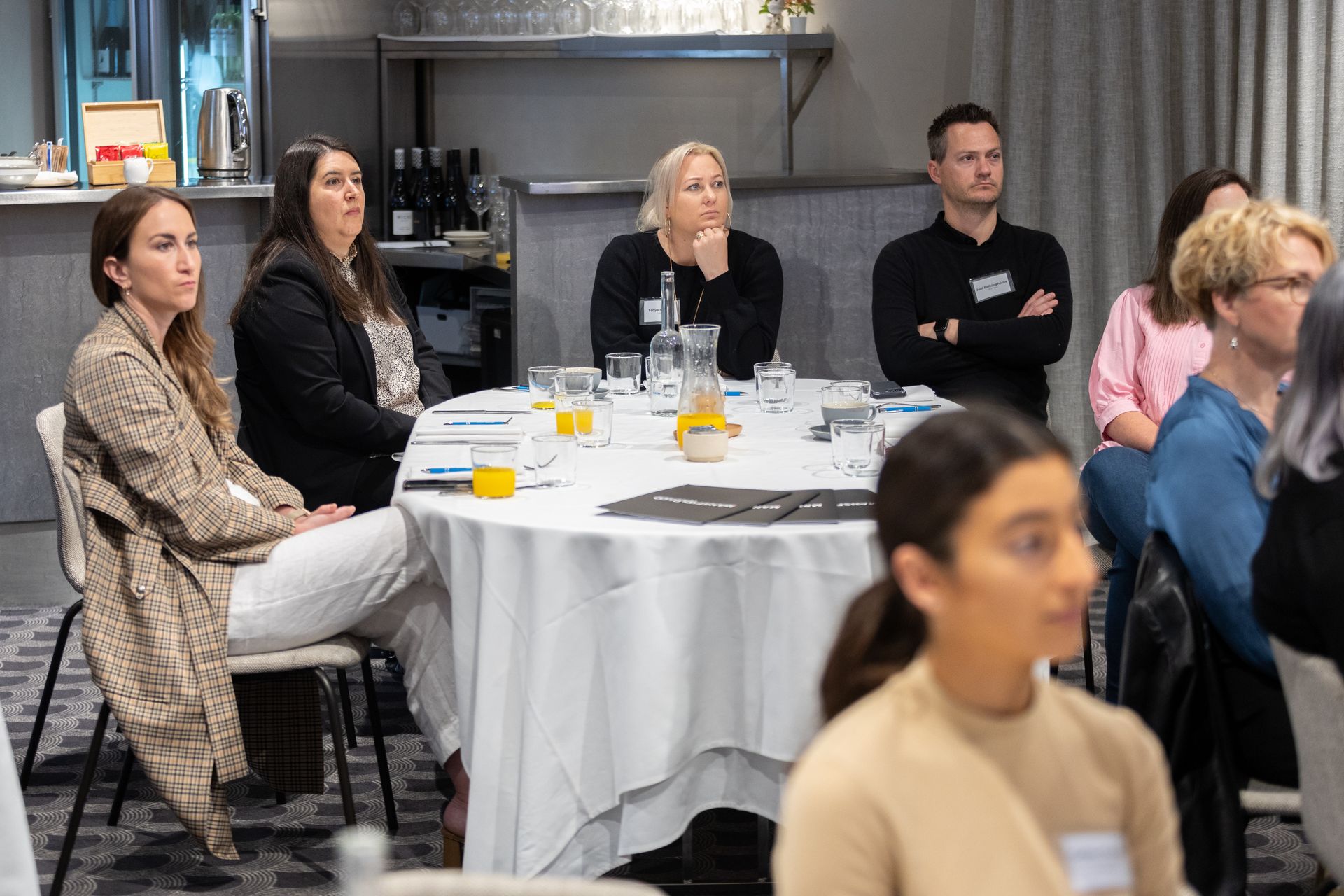 A group of people are sitting at a table watching a presentation.