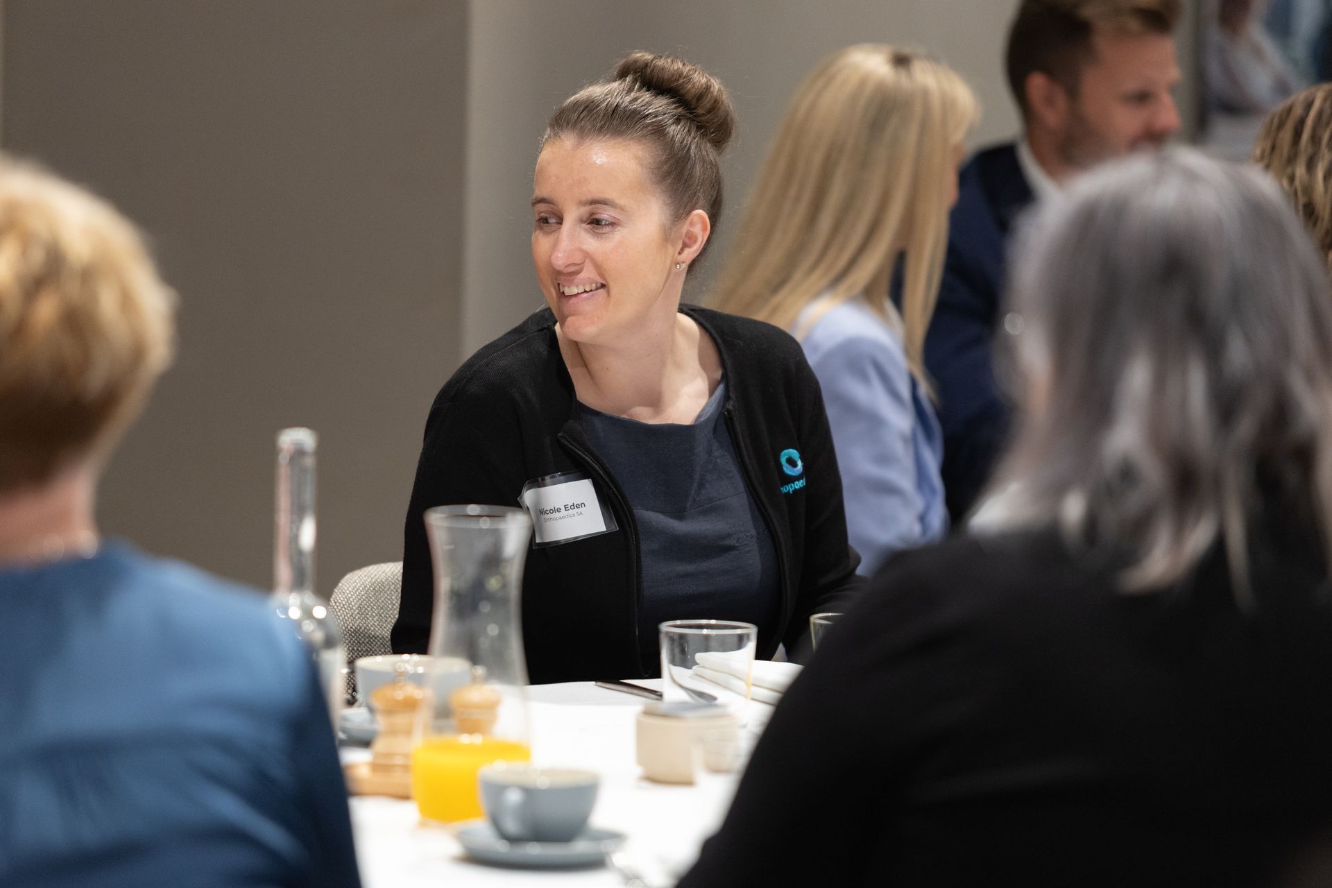 A woman is sitting at a table talking to a group of people.