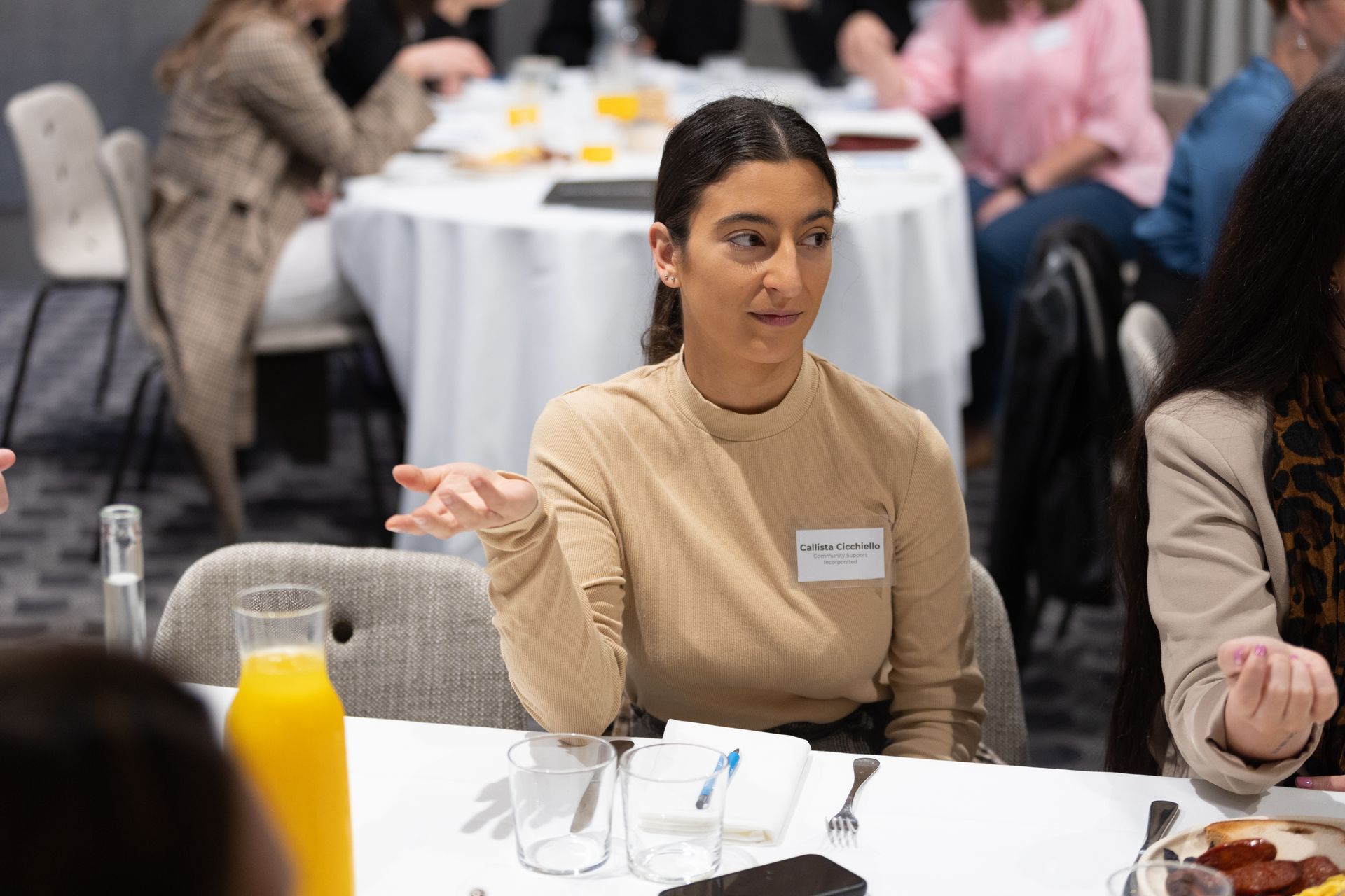 A woman is sitting at a table talking to a group of people.