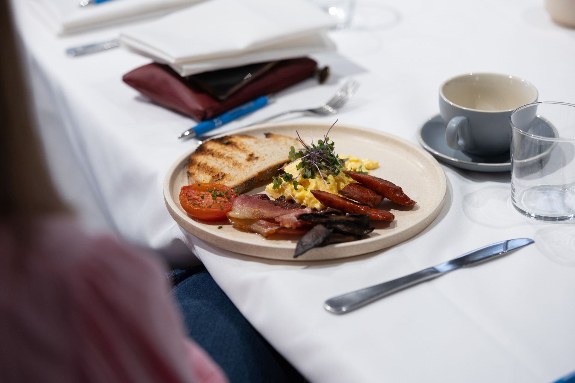 A plate of food with eggs , bacon , tomatoes and toast on a table.