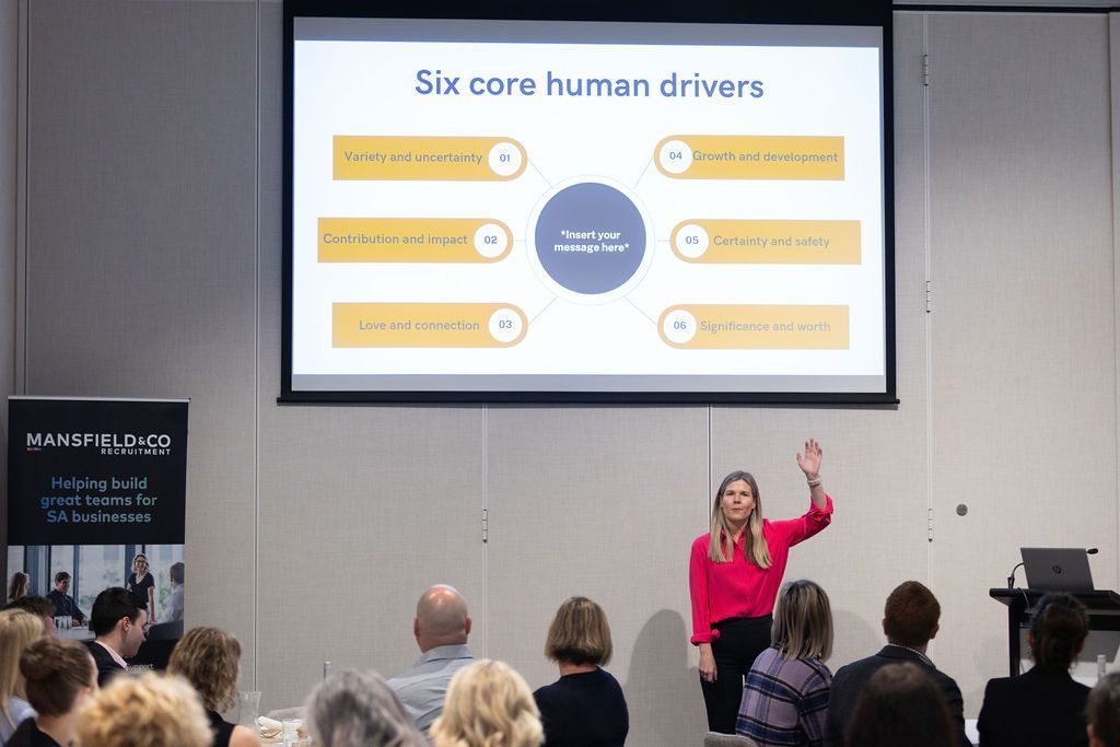 A woman is giving a presentation to a group of people in front of a large screen.