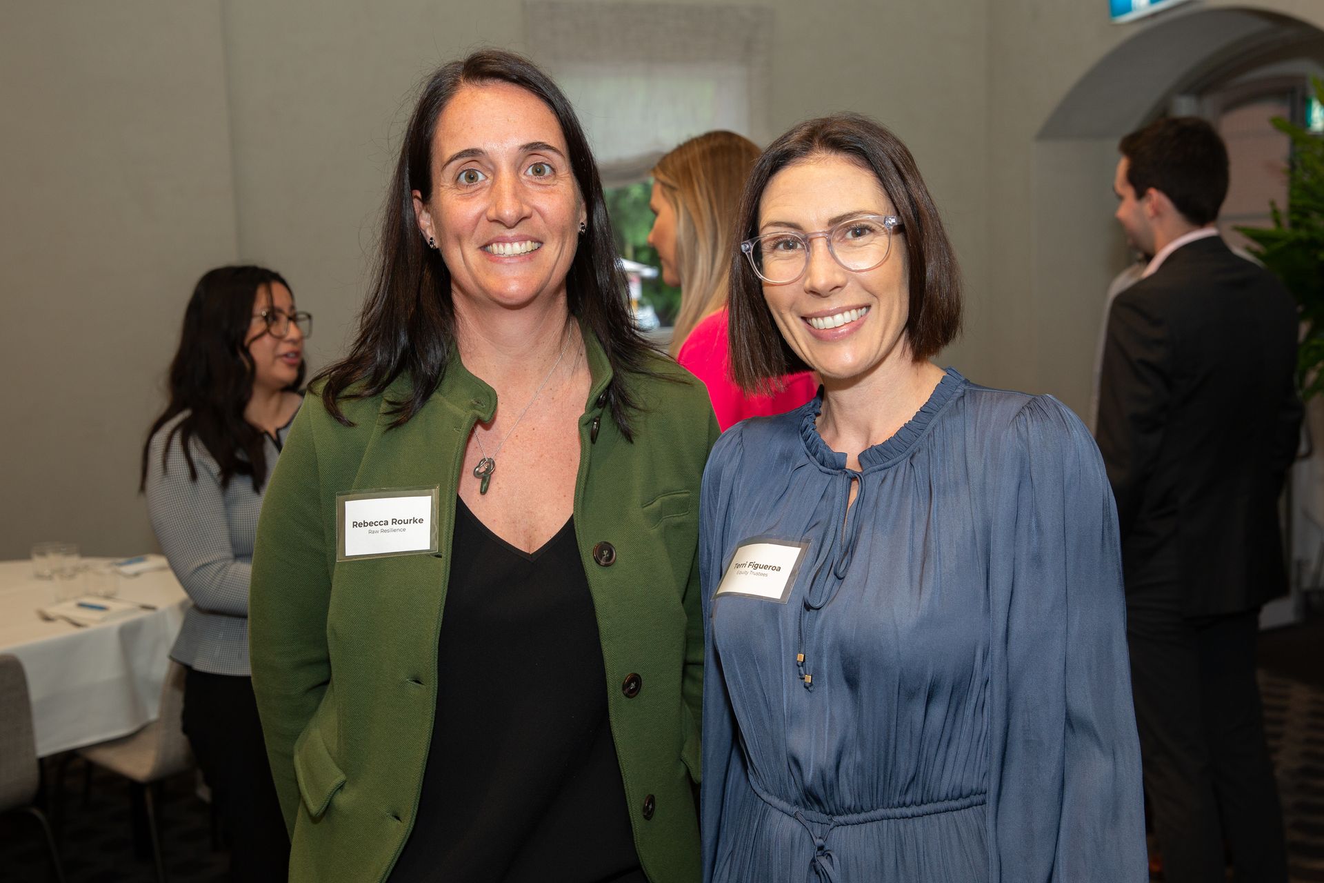 Two women are posing for a picture together at a conference.