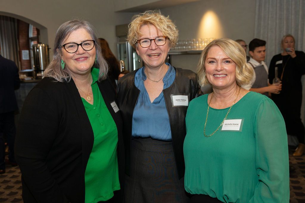 Three women are posing for a picture together in a room.