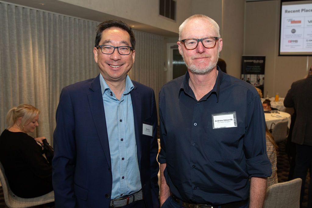 Two men are standing next to each other in a room and smiling.