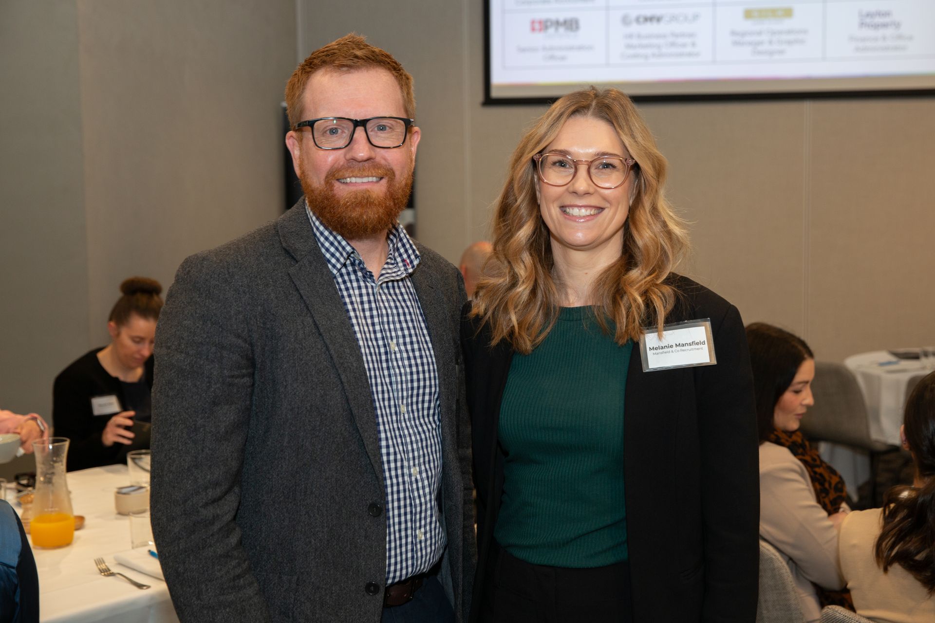 A man and a woman are posing for a picture at a conference.