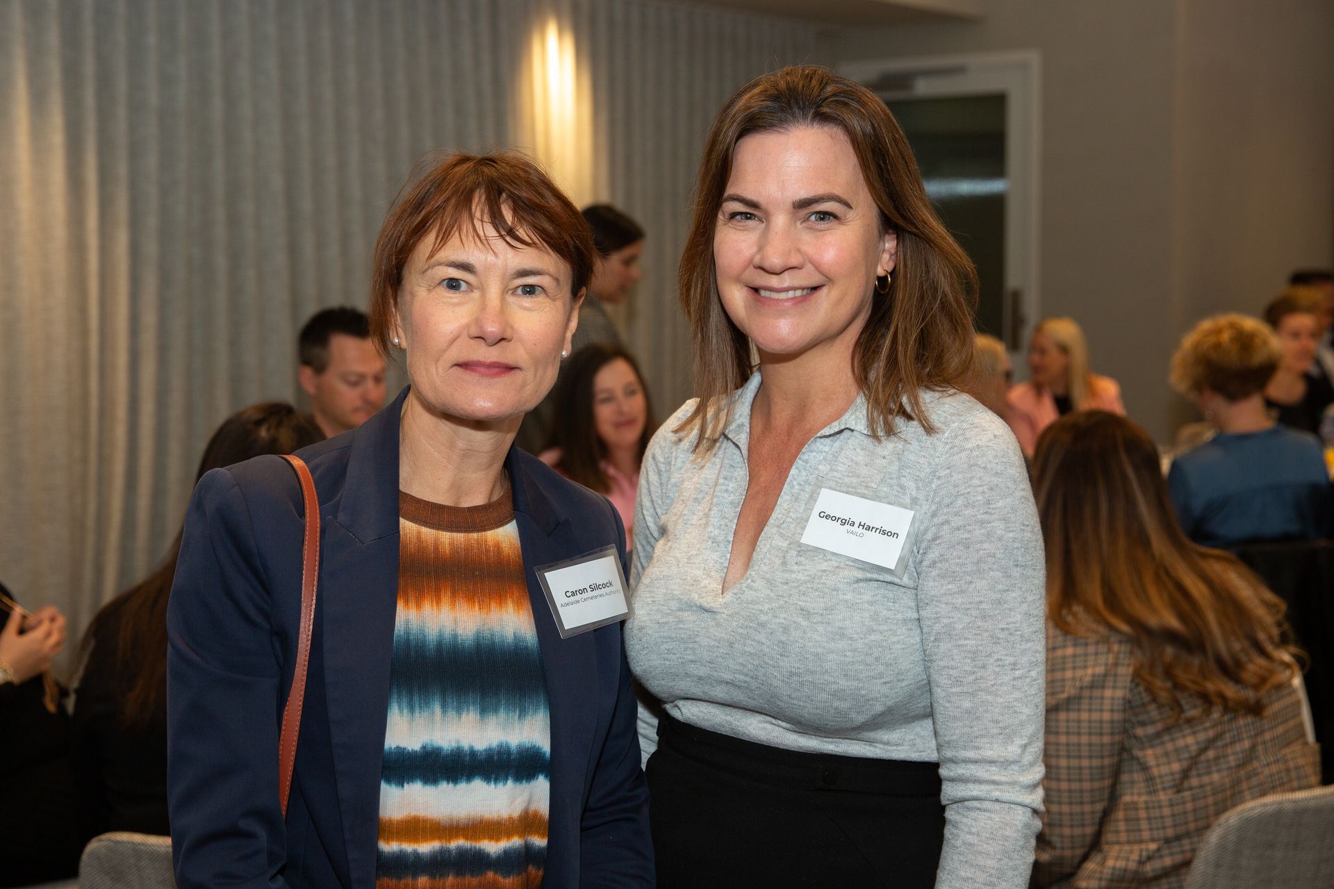 Two women are posing for a picture together at a conference.