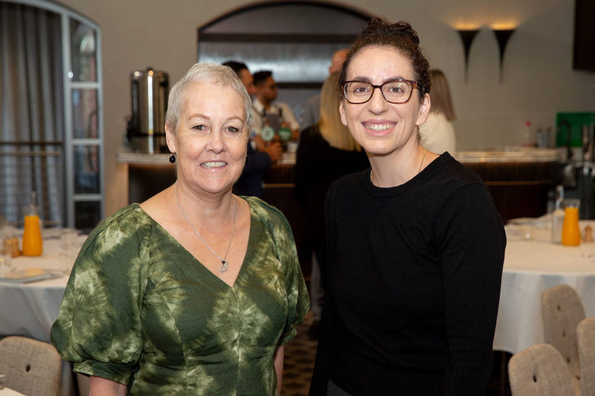Two women are posing for a picture together in a restaurant.