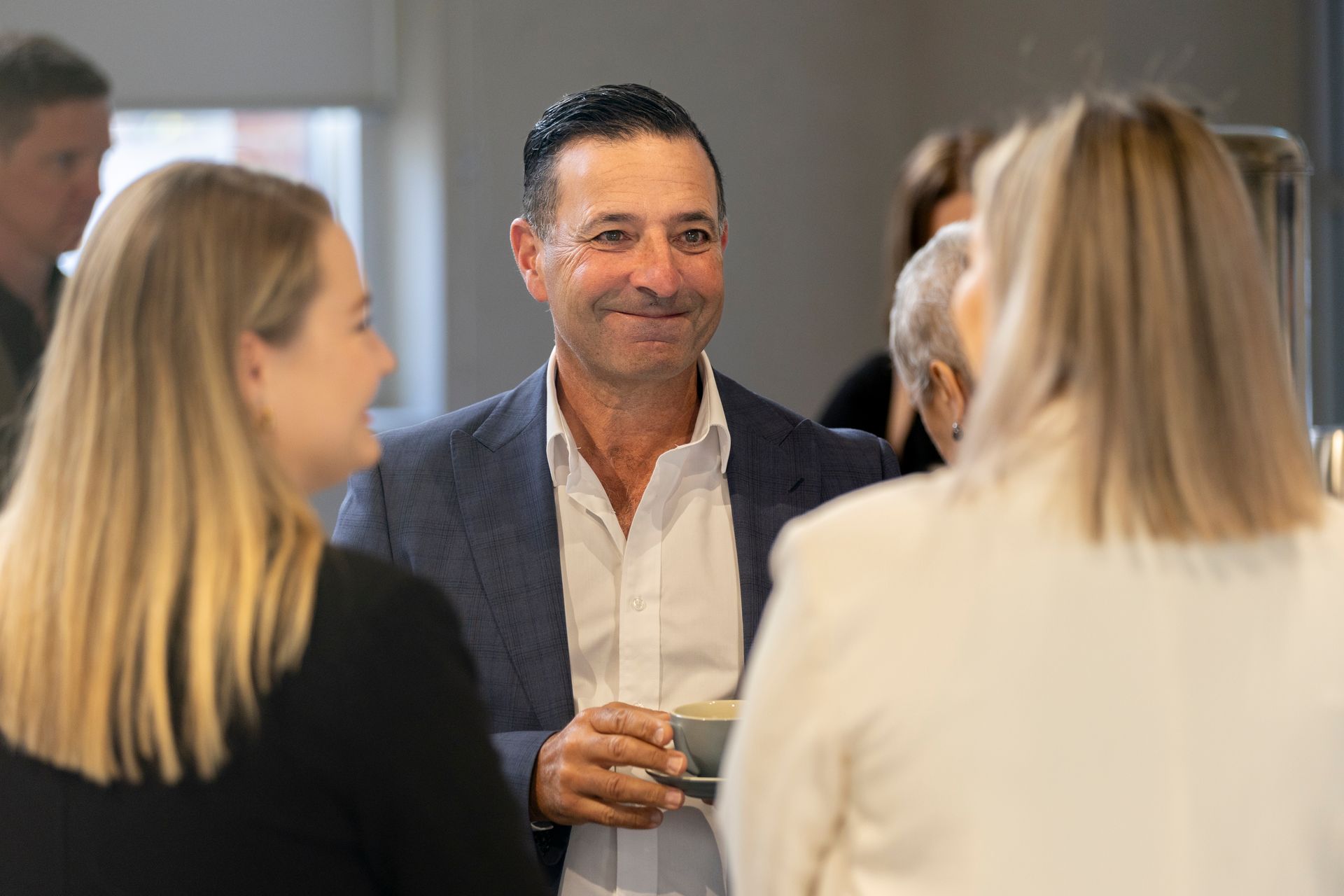 A man in a suit is talking to two women in a room.