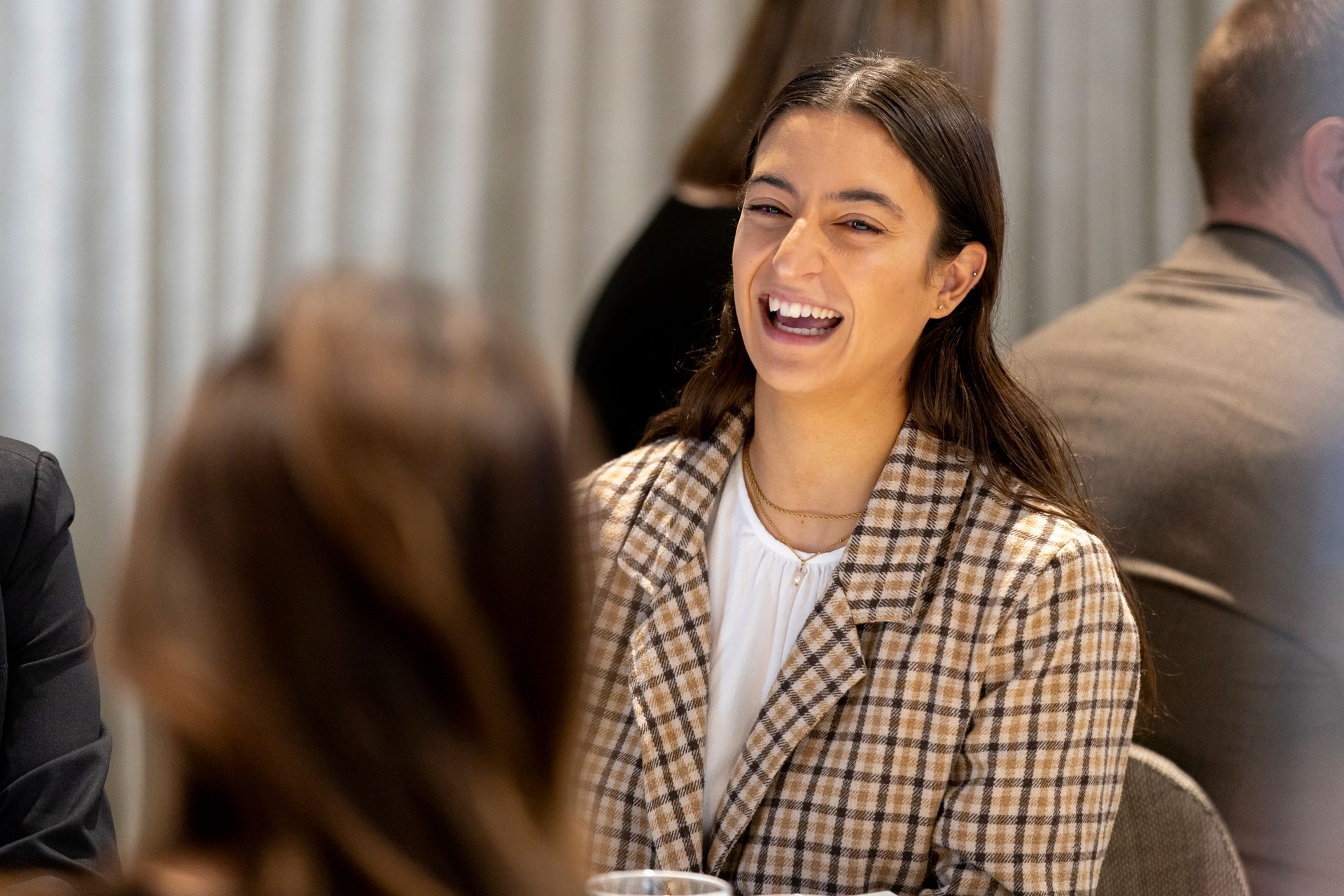 A woman is laughing while sitting at a table with other people.