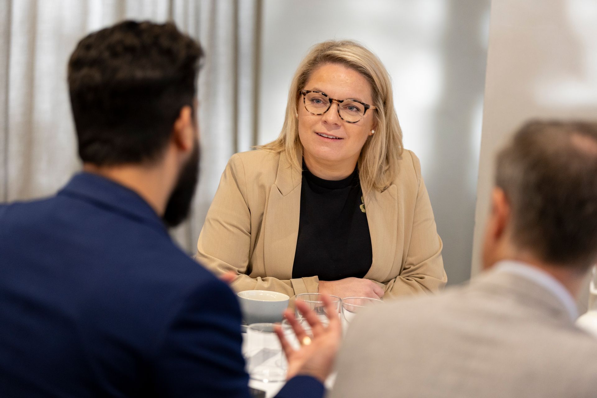A woman is sitting at a table talking to two men.