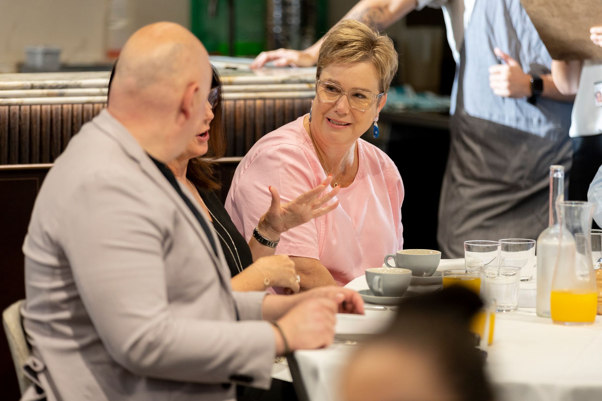 A group of people are sitting at a table talking to each other.