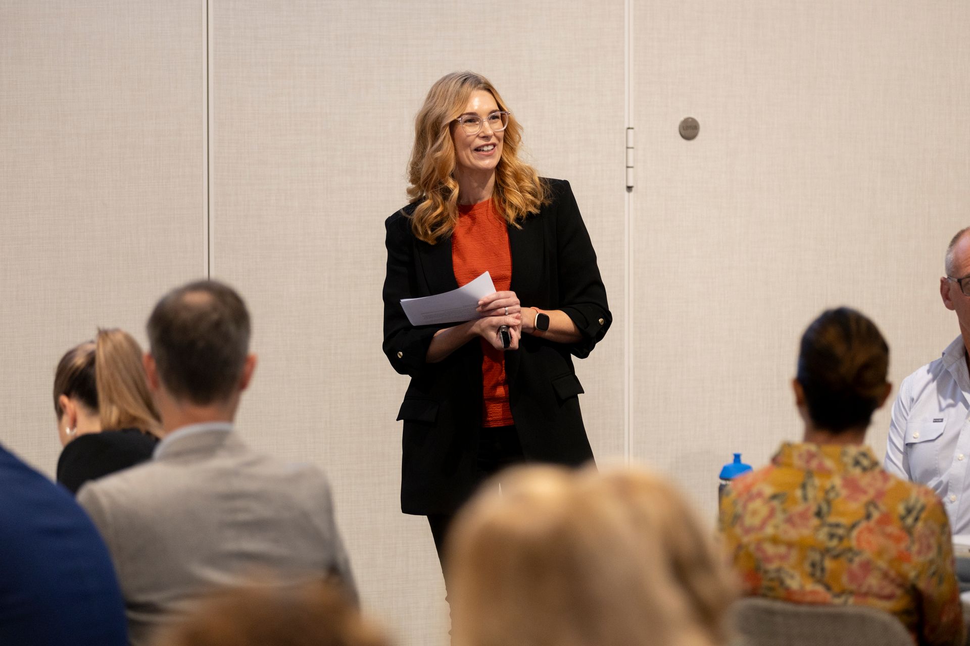 A woman is standing in front of a group of people giving a presentation.