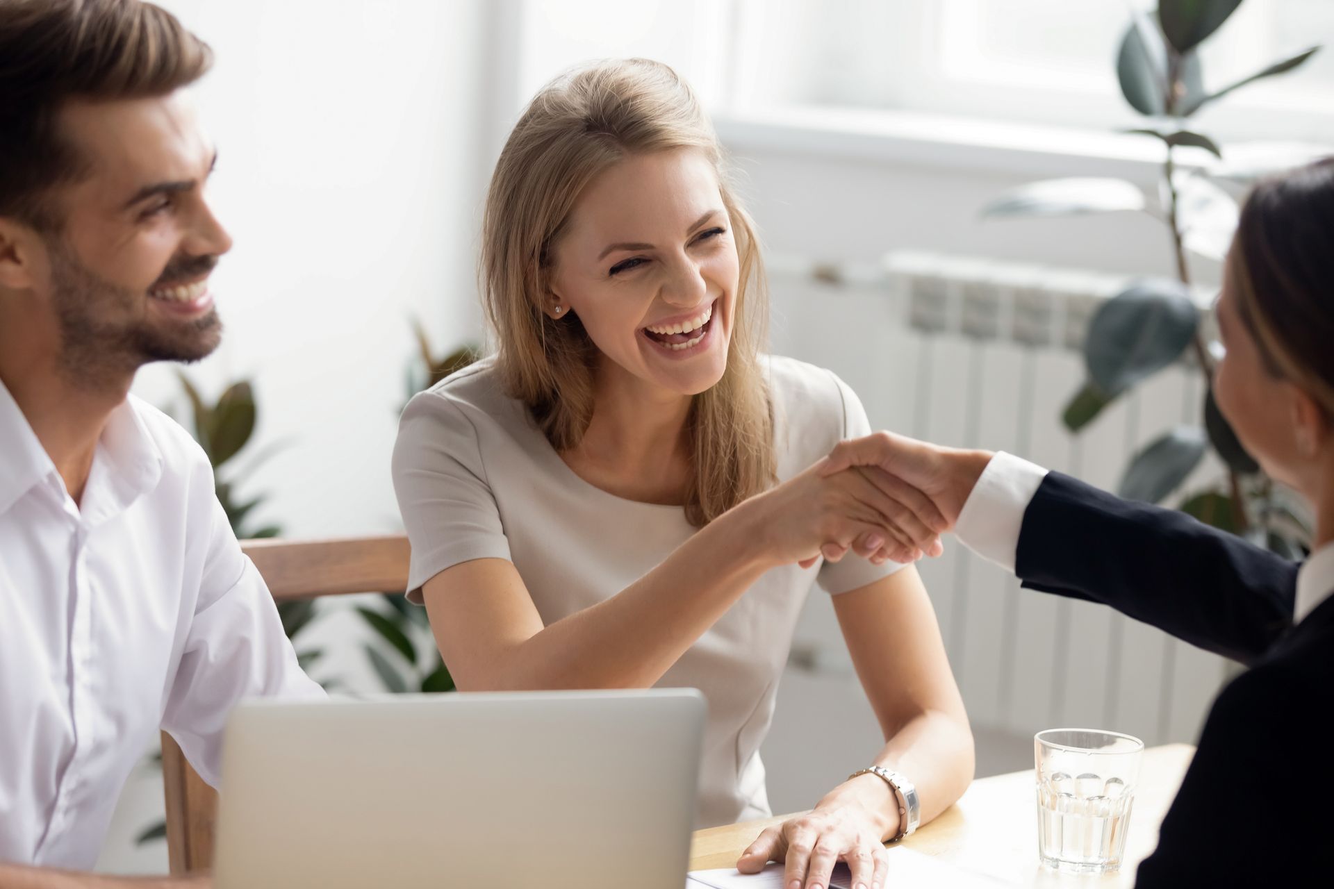 Excited laughing businesswoman shaking hand of business partner at successful meeting