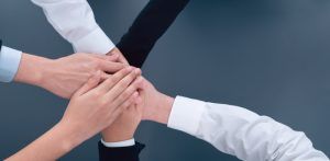 A group of people are putting their hands together in a circle.