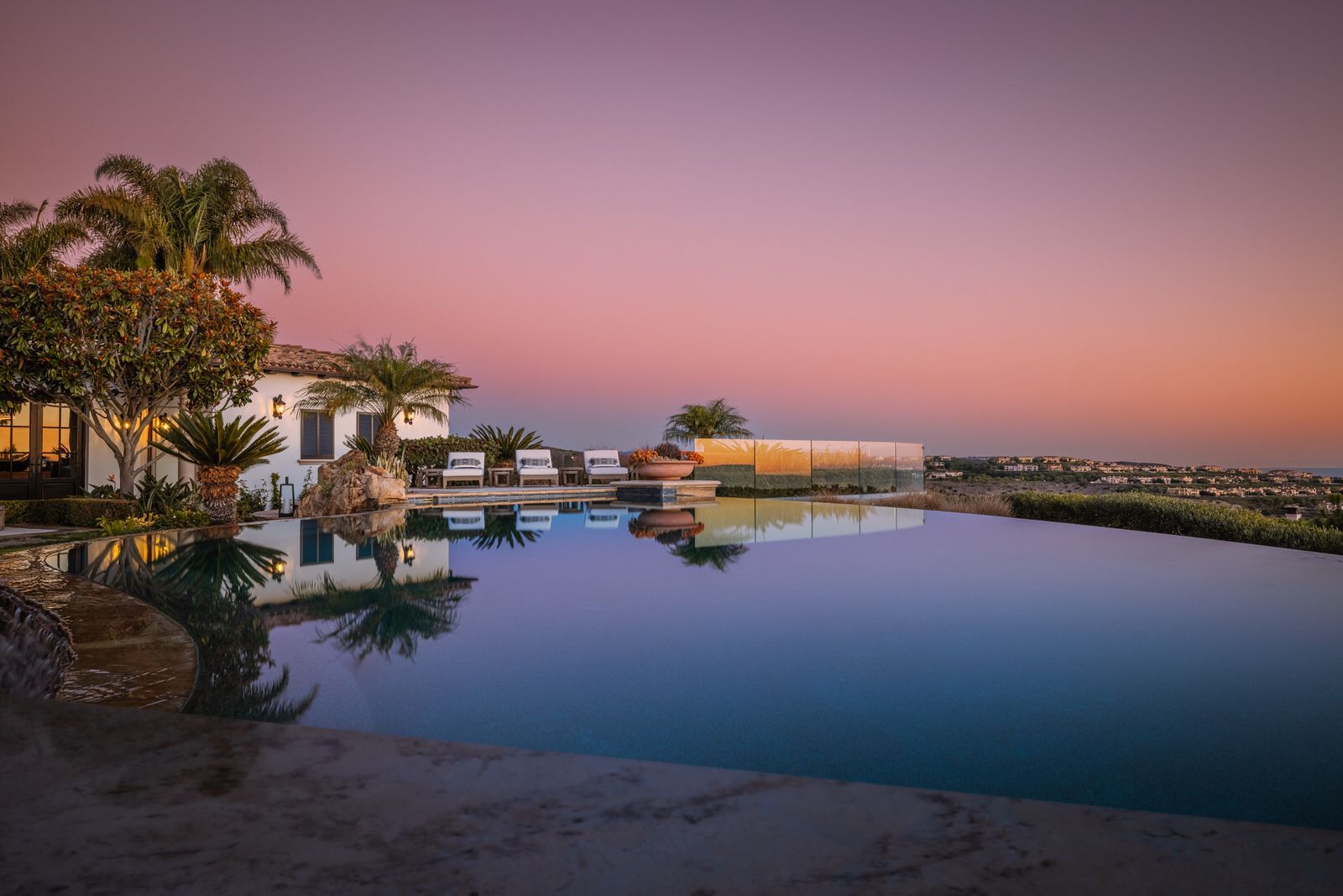 A large swimming pool with a house in the background at sunset.