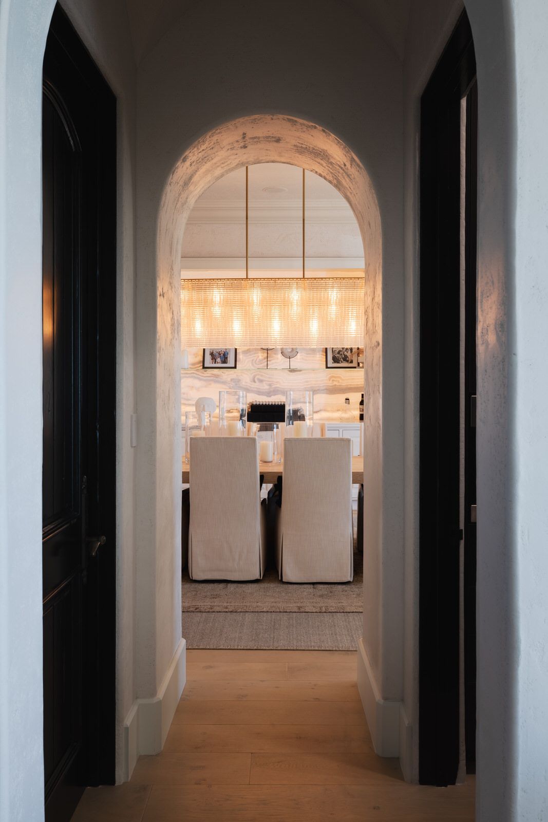 A hallway leading to a dining room with chairs and a chandelier.