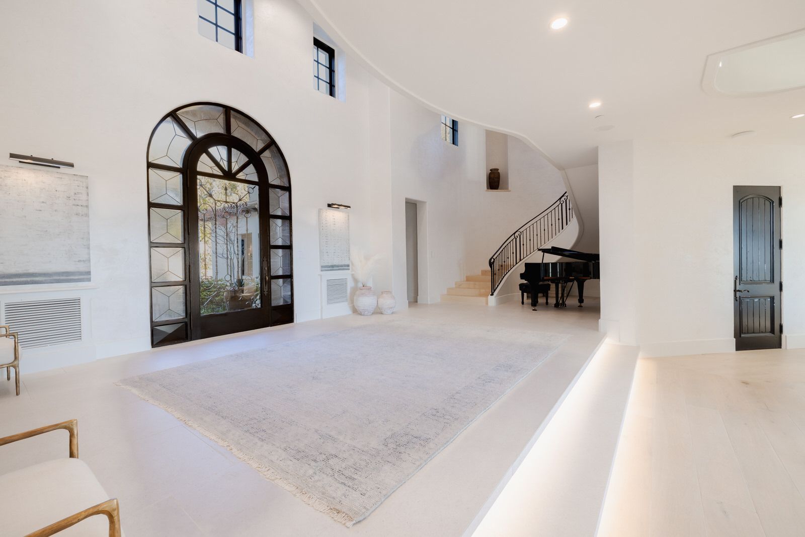 A large white room with a piano and stairs.