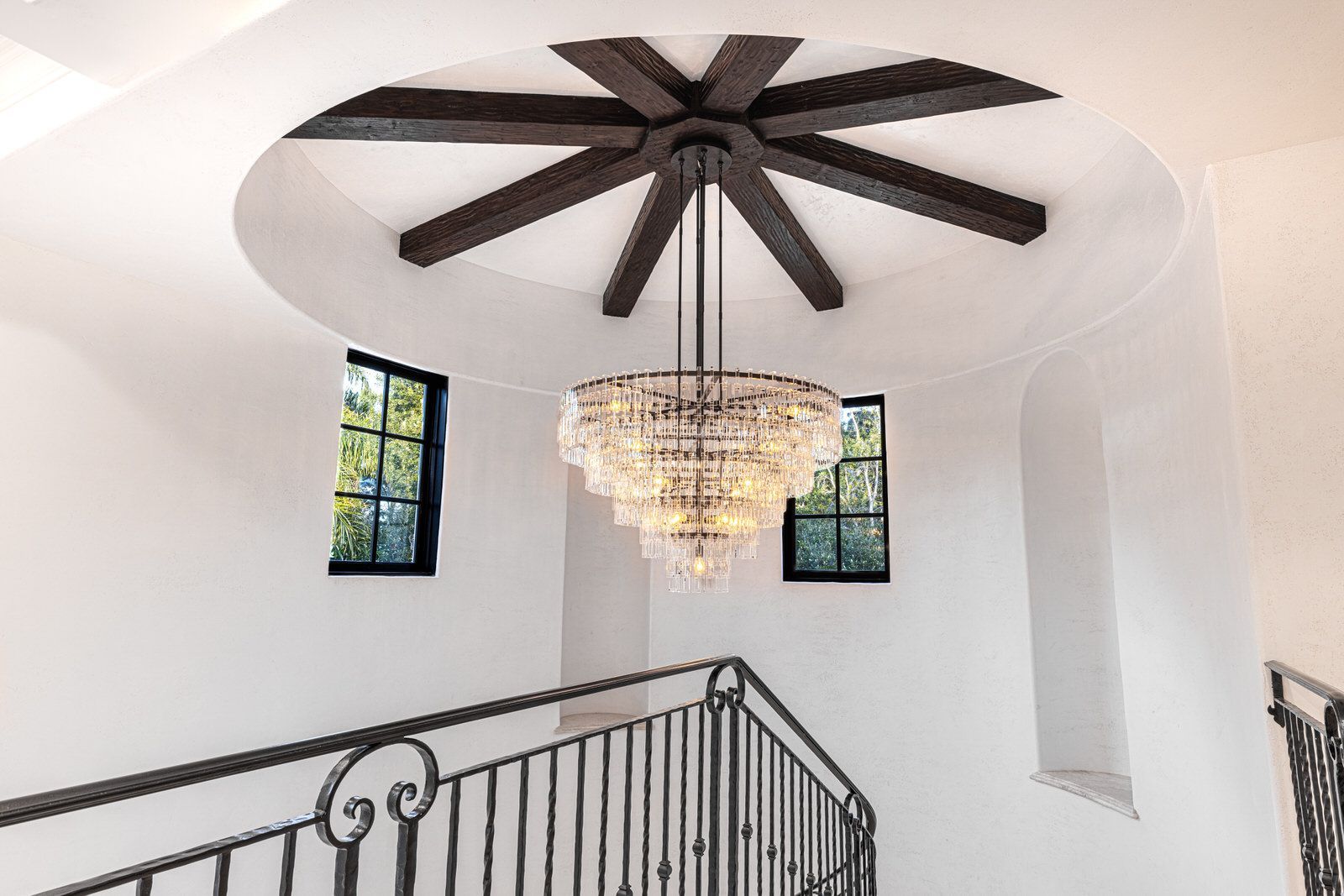 A chandelier is hanging from the ceiling of a room next to a staircase.