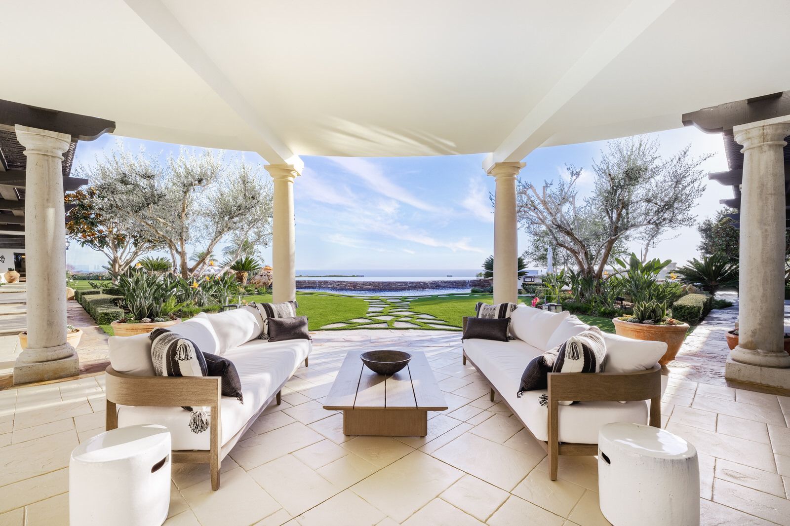 A patio with a lot of furniture and a view of the ocean.
