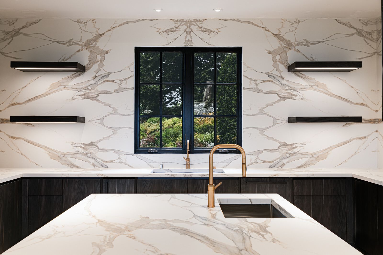A kitchen with marble counter tops , a sink , and a window.