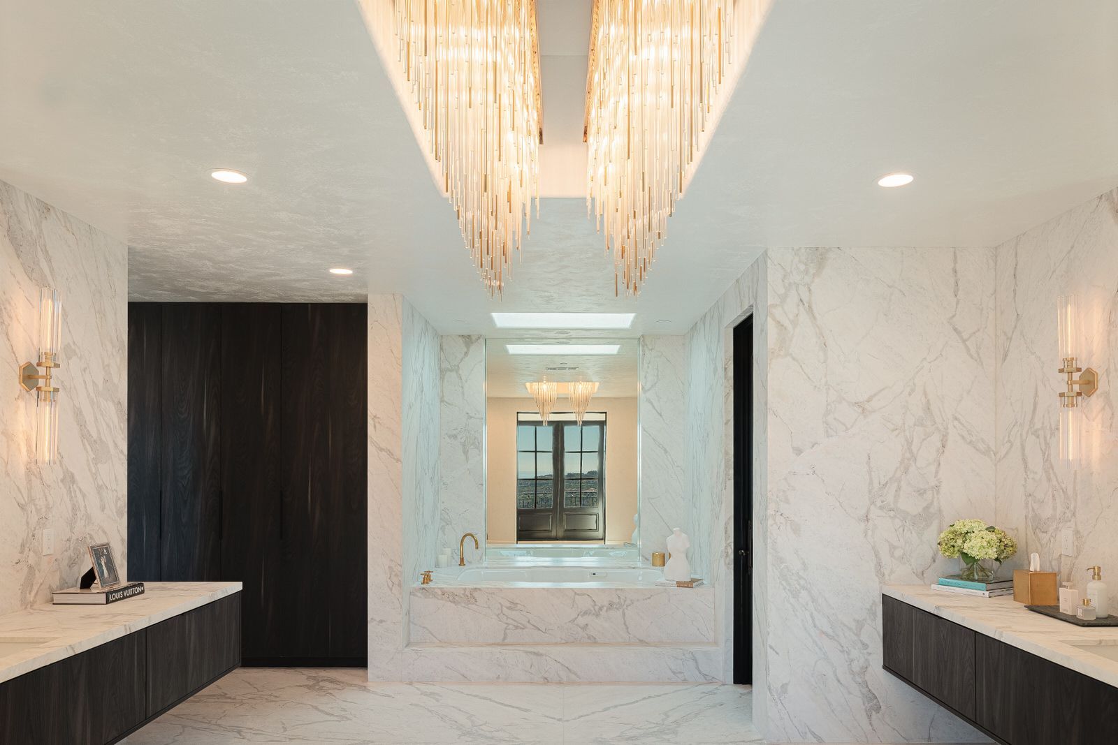 A large bathroom with marble walls and a chandelier hanging from the ceiling.