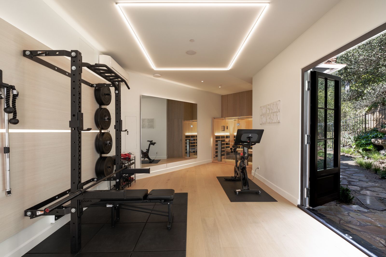 A home gym with a bench , exercise bike , and mirror.