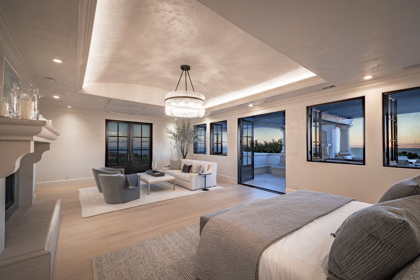 A bedroom with a large bed , fireplace , couch and chairs.
