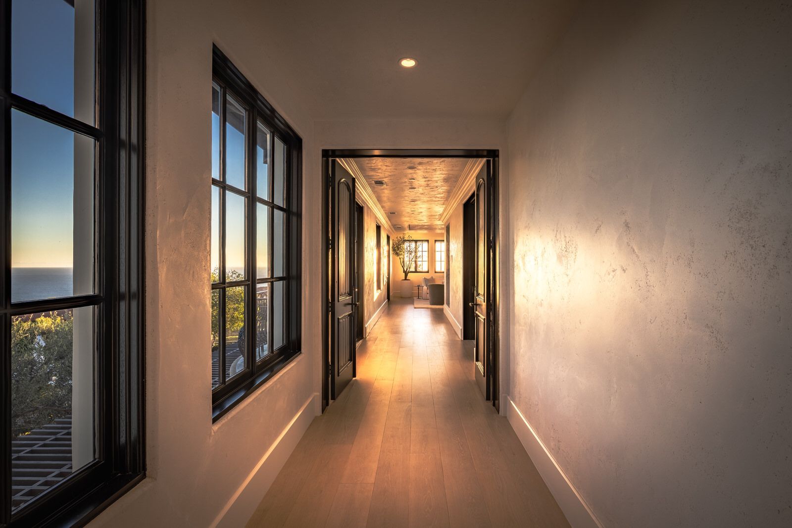 A long hallway with lots of windows and a view of the ocean.