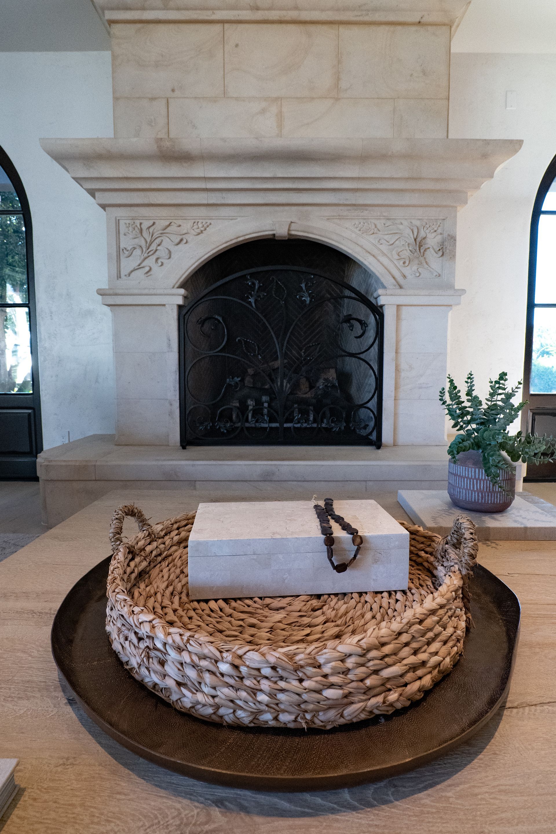 A wicker basket is sitting on a tray in front of a fireplace.