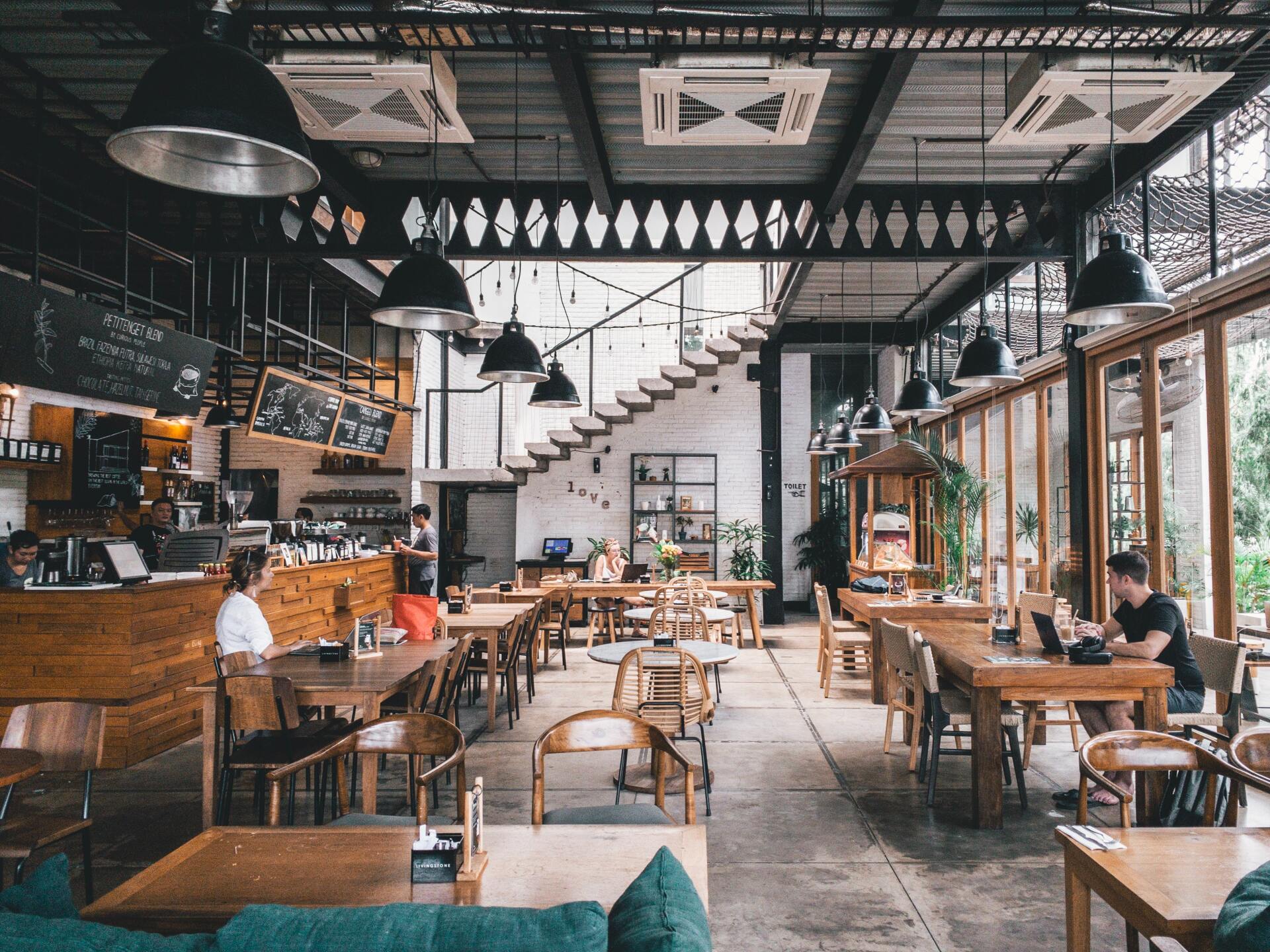 A restaurant filled with tables and chairs and people sitting at them.
