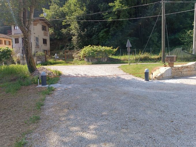 Ingresso carrabile con pilastri in mattoni e una sbarra di sicurezza arancione chiusa.