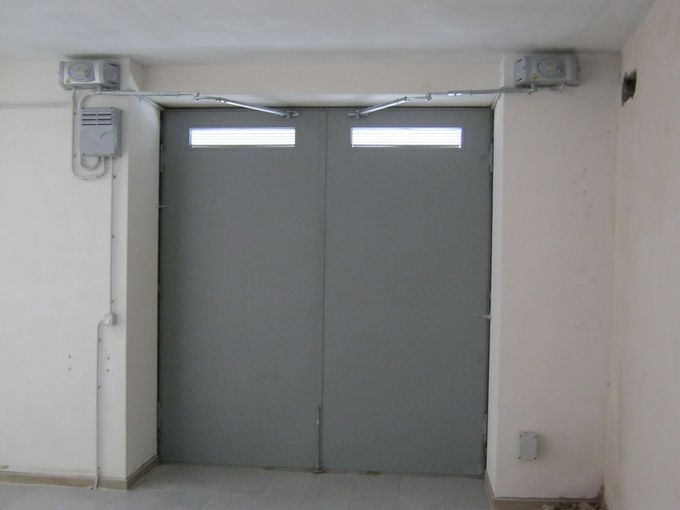 Doppie porte grigie chiuse in un corridoio spoglio con piccole finestre sopra di esse