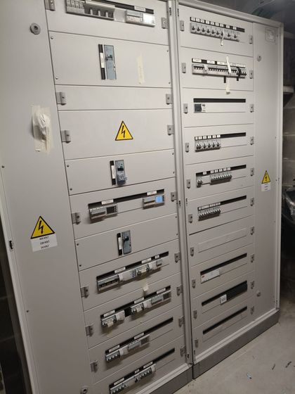 Quadro elettrico aperto con file di interruttori automatici e fili blu, marroni e rossi