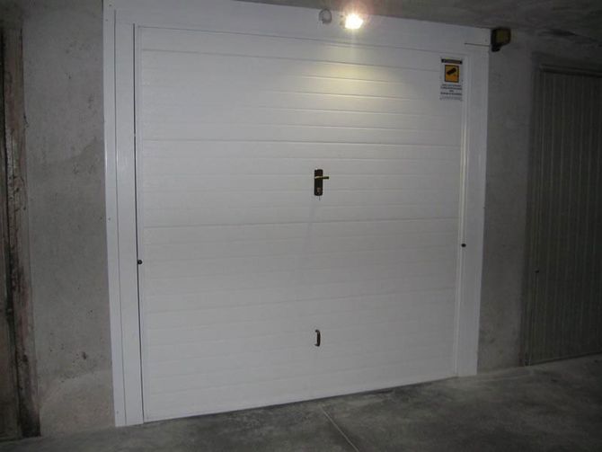 Porta da garage bianca in un'area di parcheggio in cemento con luce soprastante.