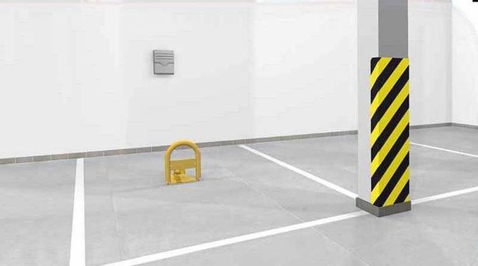 Parcheggio sotterraneo vuoto con un bloccasterzo giallo vicino a un pilastro di sostegno a strisce.