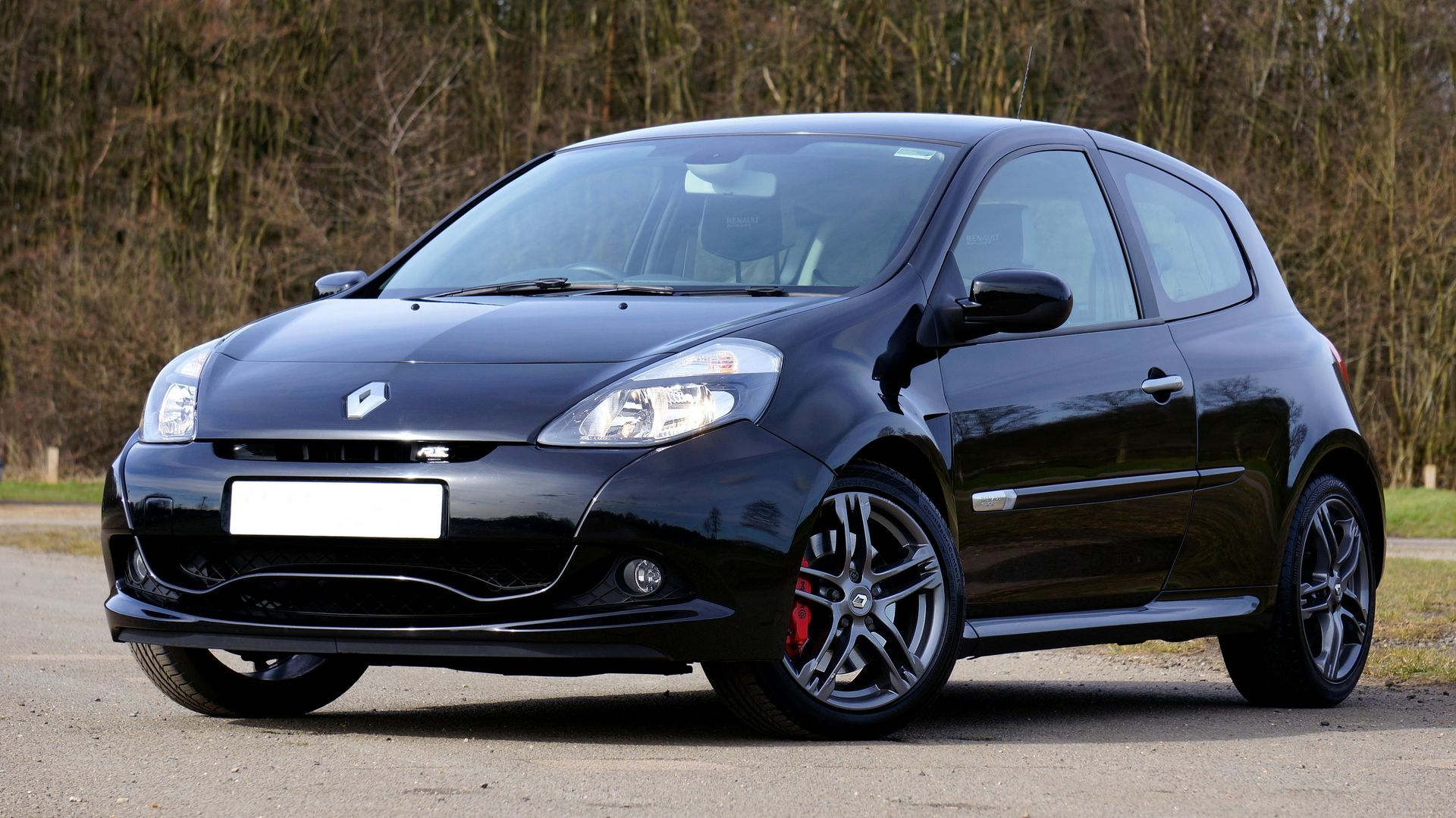 Black compact hatchback car parked on a road, shown in side front view.