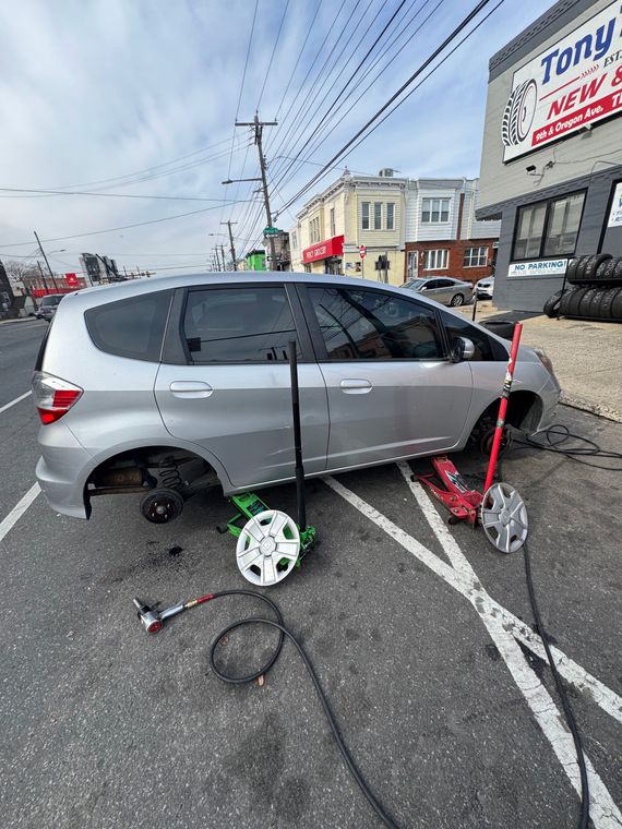 Silver minivan in crash scene with damaged wheel, cords, and a utility pole on a street corner