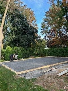 Un homme travaille sur une base en béton dans une arrière-cour.