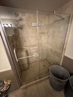 Une salle de bain avec douche à l'italienne et poubelle.
