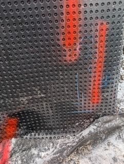 Des lumières rouges scintillantes derrière un panneau métallique perforé, avec un sol enneigé en dessous.