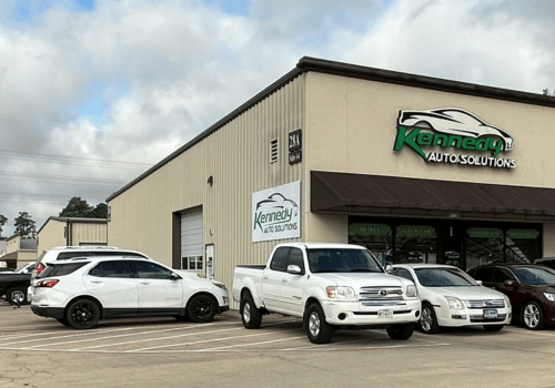 Kennedy Auto Solutions building with several parked vehicles outside under a cloudy sky