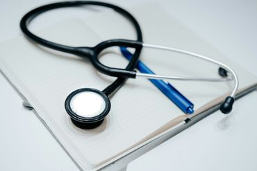 Stethoscope and blue pen on a white notepad, symbolizing medical notes or healthcare work